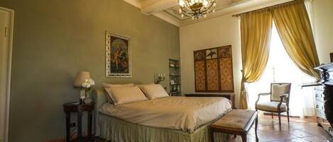 Un dormitorio con una cama grande, un candelabro, un escritorio y una silla.