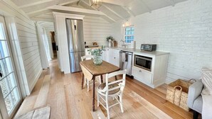 Uma cozinha espaçosa com piso de madeira, armários brancos e um espaço de refeições com mesa e cadeiras.