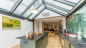 Et moderne køkken med en central ø, et spiseområde og udsigt gennem et glasloft.
