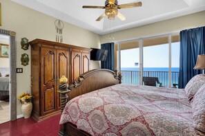 Ein Schlafzimmer mit einem großen Bett, einem Holzschrank, einem Deckenventilator, einem Fernseher und Meerblick.