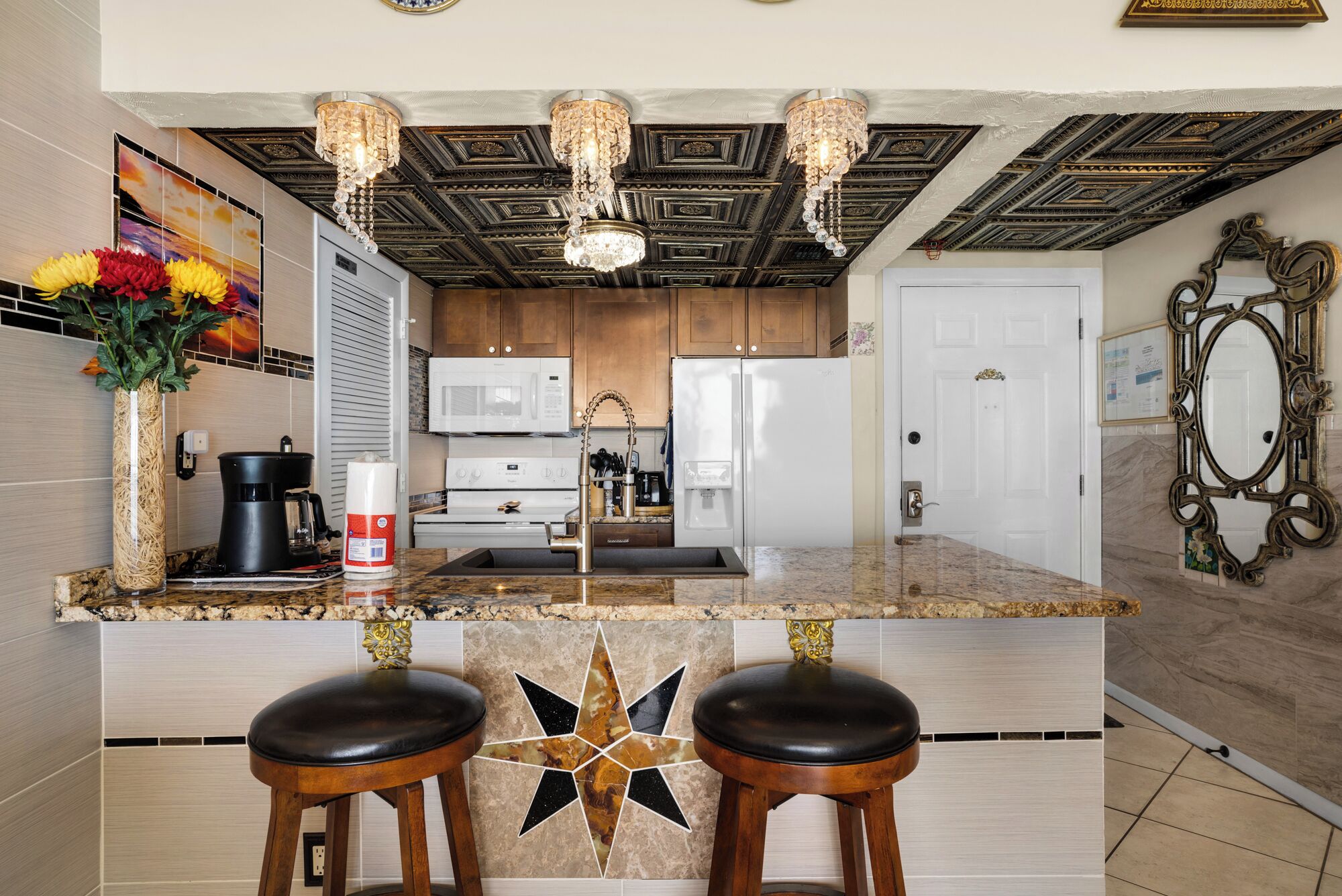 A modern kitchen with a central island, stainless steel appliances, and decorative lighting.