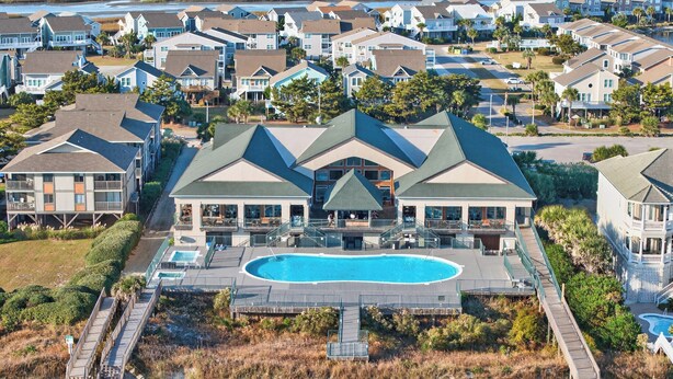 Ein großes Resort mit einem zentralen Pool, zahlreichen Gästezimmern und einem Weg zum Strand.