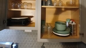 Una cocina con dos alacenas abiertas que contienen diferentes platos y cristalería.