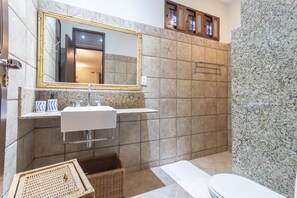 Une salle de bain avec un grand miroir, un lavabo blanc et un espace douche.