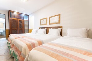 Une chambre d’hôtel avec deux lits, une armoire en bois et deux tableaux encadrés au mur.