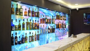 Un espace bar avec des étagères remplies de différentes bouteilles d’alcool et un comptoir en marbre.