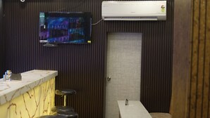 Un espace bar avec un téléviseur fixé au mur, un comptoir et des tabourets.