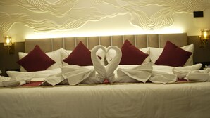 Une chambre d’hôtel avec un lit agrémenté d’oreillers décorés d’un motif de cygne et d’un mur au revêtement texturé.