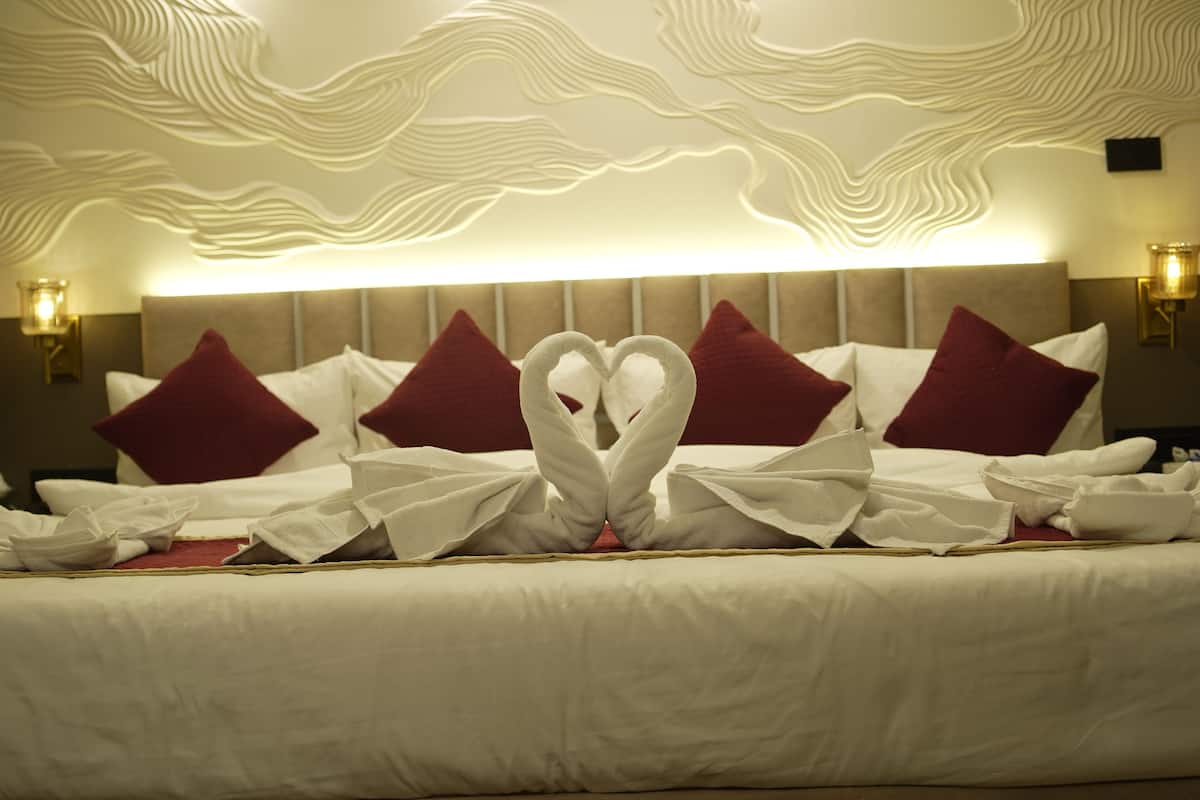 Habitación de hotel con cama, almohadas con un diseño decorativo de cisne y un diseño de pared texturizado.