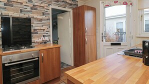 A modern kitchen with a built-in oven, wooden cabinets, and a stone backsplash. - Beechtree Lodge 57 (Denny)