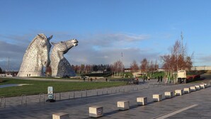 A public square with a large metallic sculpture, a paved walkway, and a grassy area. - Beechtree Lodge 54 (Denny)
