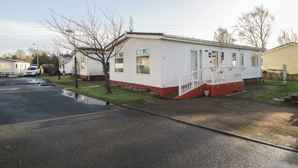 A single-story mobile home with a front porch and a small front yard. - Beechtree Lodge 54 (Denny)
