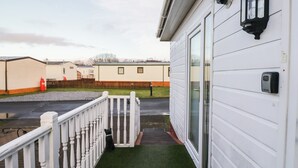 A white mobile home with a small porch and a green artificial lawn. - Beechtree Lodge 54 (Denny)