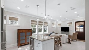 A spacious kitchen with a central island, wooden cabinets, and a dining area with wicker chairs. - 🏖️2BR Sea La Vie Seaside • Steps to Private Beach Access•Bikes🏖️ (Santa Rosa Beach)