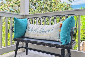A bench with a cushion that has embroidered text, surrounded by a railing with a view of greenery. - ⛱️Beach Access | Pet Friendly | Azure on 30A 1-205- A Wave From it All⛱️ (Santa Rosa Beach)