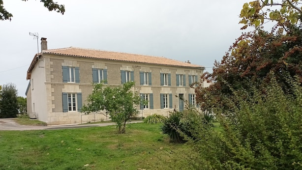 A two-story building with a tiled roof and multiple windows.
