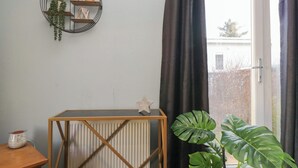A room with a radiator, a wooden table, a decorative shelf with plants, a star-shaped ornament, and a large green plant. - Beechtree Lodge 55 (Denny)