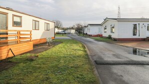 A row of mobile homes with a grassy area and a paved road in between. - Beechtree Lodge 55 (Denny)
