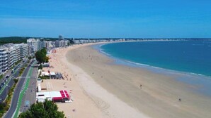 A coastal beach with a road running parallel to the shore, lined with buildings and a red structure. - Bright apartment in the countryside - private parking (Fontaines-d'Ozillac)