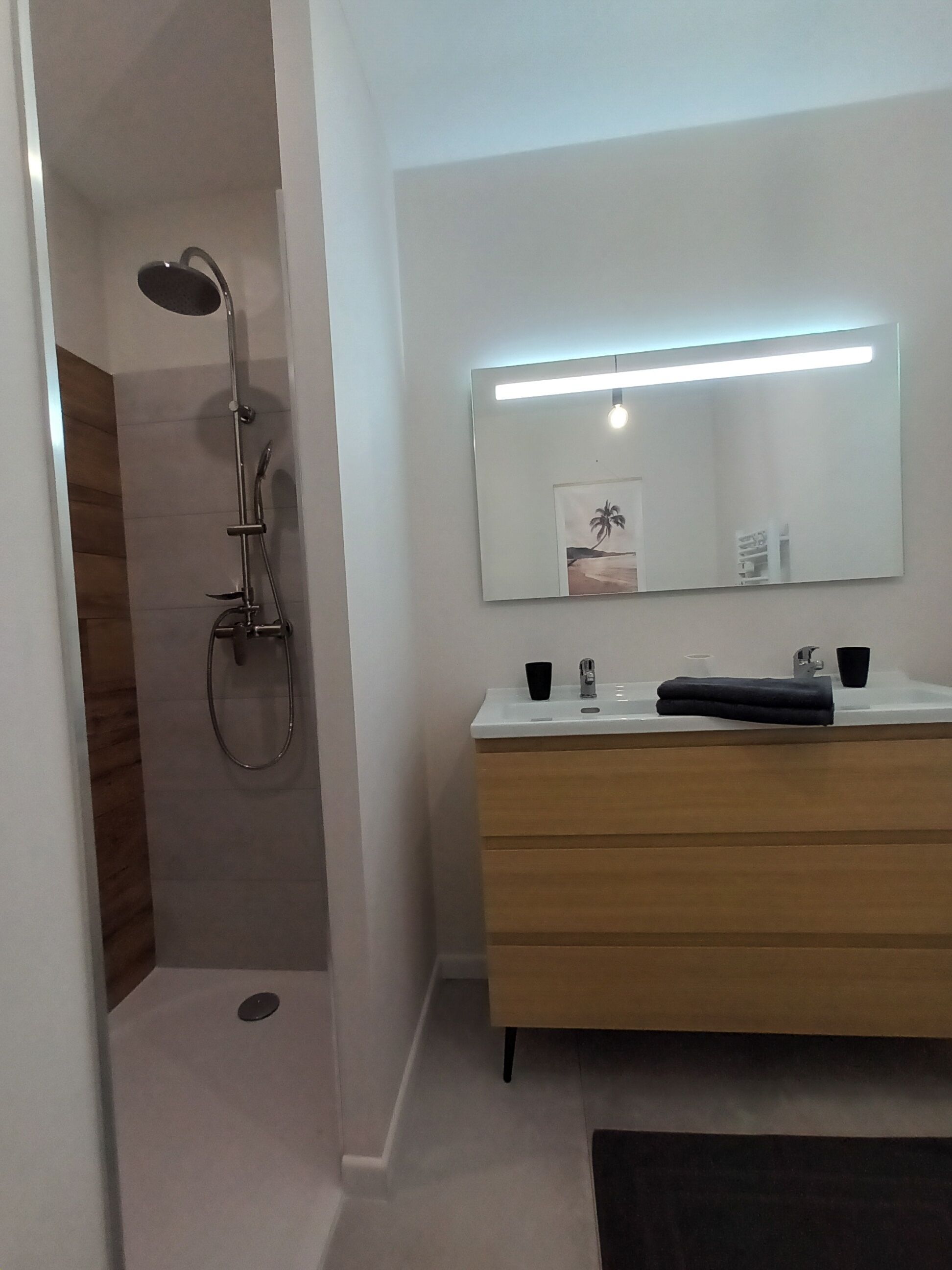 A modern bathroom with a shower, a vanity with a mirror, and a towel.