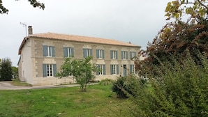 A two-story building with a tiled roof and multiple windows. - Bright apartment in the countryside - private parking (Fontaines-d'Ozillac)