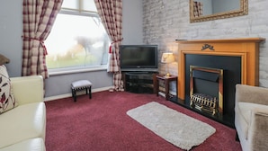 A living room with a fireplace, a television, and a window with curtains. - Beechtree Lodge 46 (Denny)