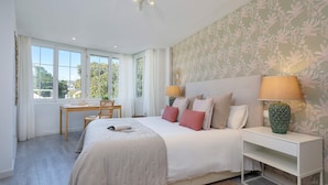 A bedroom with a large bed, bedside lamps, a desk, and a view through the window. - Genteel Home Plaza del Teatro II (Malaga)