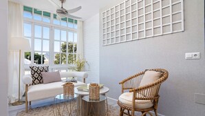 A room with a white sofa, a wicker chair, a glass coffee table, and a patterned rug. - Genteel Home Plaza del Teatro II (Malaga)