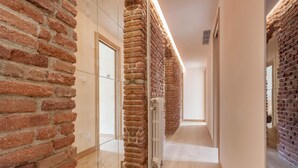 A hallway with brick walls, a radiator, and a glass partition. - Genteel Home Concha Espina I (Madrid)