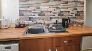 A kitchen with a wooden countertop, a sink, a coffee maker, and a wall with a wooden plank backsplash. - Beechtree Lodge 56 (Denny)