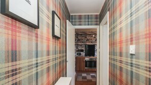 A hallway with plaid wallpaper, a bench, and a kitchen area with a microwave and oven. - Beechtree Lodge 56 (Denny)