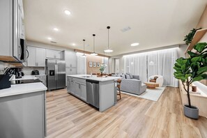 A modern kitchen with stainless steel appliances, a central island, and pendant lighting. - 5BR house with spa near Disney area (Kissimmee)