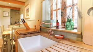 A kitchen with a wooden countertop, a sink, and a window with blinds. - The Hayloft - Beautiful Barn Stay (Ashford)