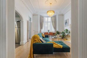 Un salón amplio con un sofá verde, una araña y un comedor con una mesa y sillas.