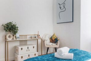 Una camera da letto ordinata con un letto, una sedia, una scrivania e un'opera d'arte appesa al muro.