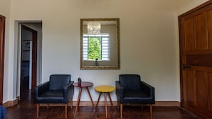 A room with two black leather chairs, a small round table, and a mirror on the wall. - Apartamento Pet Friendly com Garagem no Nova Su a (Belo Horizonte)