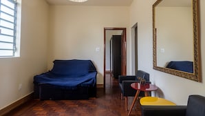 A room with a bed, a sofa, a small table, and a mirror. - Apartamento Pet Friendly com Garagem no Nova Su a (Belo Horizonte)