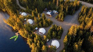 An aerial view of a lakeside cabin complex with yurts, a main lodge, and a dock with kayaks. - Nordika | Lakefront | Hot tub | Fireplace (Matawinie Regional County Municipality)