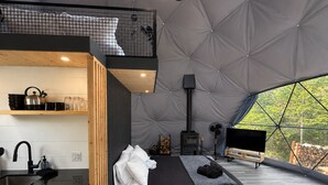 Ein modernes Zelt-ähnliches Zimmer mit Bett, einer Küchenzeile, einem Kamin und einem Fernseher.