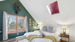 A bedroom with a bed, bedside tables, a fan, and a window with curtains. - Deer Hollow Retreat | Fireplace, Bunk Bed, Game Rm (Albrightsville)