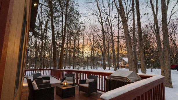 A deck with outdoor seating, a grill, and a view of a snowy forest. - Deer Hollow Retreat | Fireplace, Bunk Bed, Game Rm (Albrightsville)