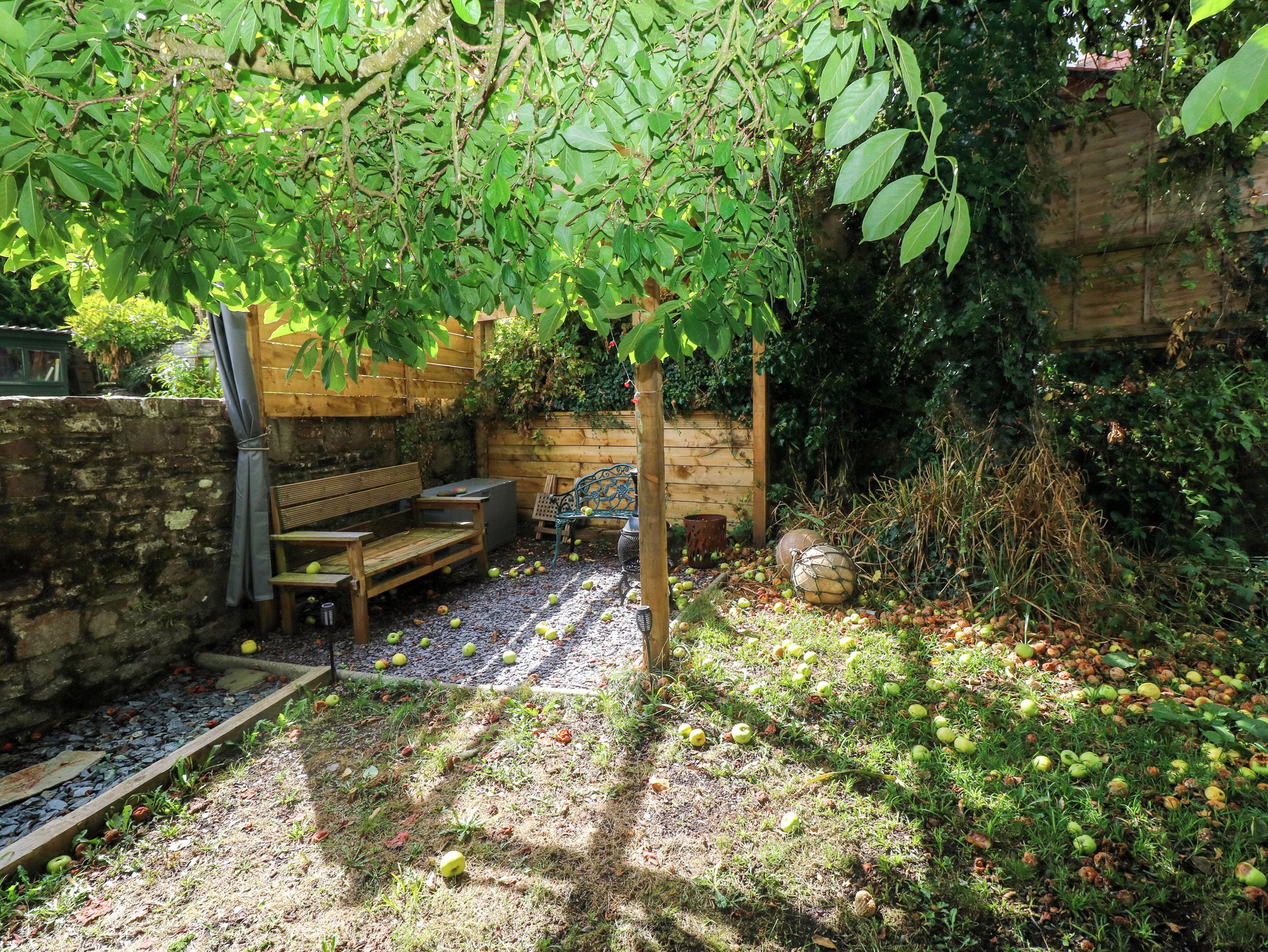 A garden area with a wooden bench, a table, and a stone wall.