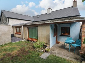 A residential property with a patio area, a small garden, and a blue exterior wall. - 2 Strand Cottages (Carmarthen)