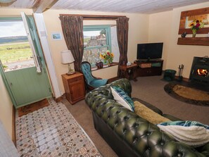 Una sala de estar con sofá, televisión, chimenea y ventana con cortinas.