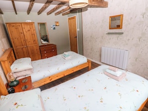 A bedroom with two single beds, wooden furniture, a dresser, a mirror, and a radiator. - 2 Strand Cottages (Carmarthen)