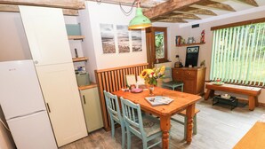 A compact kitchen with a dining table, chairs, a refrigerator, and a wooden bench.
