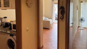 A kitchen with appliances, a clock, and a hallway leading to a bedroom. - Casa Mar apartment, very close to Meia Praia beach, the Marina and the center of Lagos. (Lagos)
