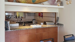 A kitchen with a granite countertop, a hanging light fixture, and a surfboard decoration. - Casa Mar apartment, very close to Meia Praia beach, the Marina and the center of Lagos. (Lagos)