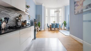 A modern kitchen with white cabinets, a black countertop, and a dining area with a blue table and chairs.