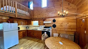 Una cocina tipo cabaña con paredes de madera, una mesa de comedor y una araña.